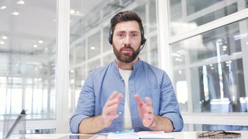Webcam view. Confident businessman in headset talking on a video call looking at camera sitting