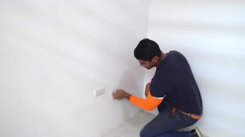Young Adult Cleaning Wall on Knees Indoors