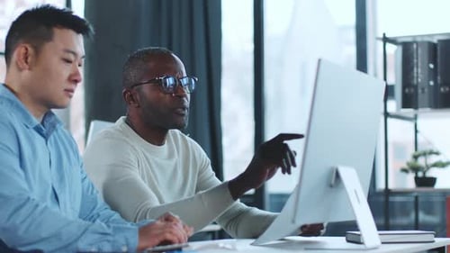 Adults Collaborate on Computer Project in Modern Office