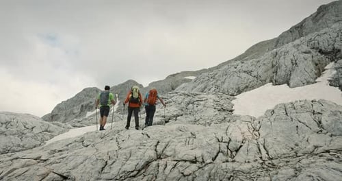 Wanderer tragen Rucksäcke und verwenden Wanderstöcke, um beim Gehen auf dem Hang oder beim Klettern auf Felsen zu helfen