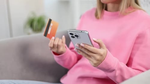 Woman making online payment with phone and credit card indoors, closeup