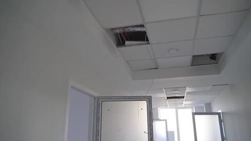 White corridor in a newly-built building. Focus on the unfinished pieces of ceiling cover.