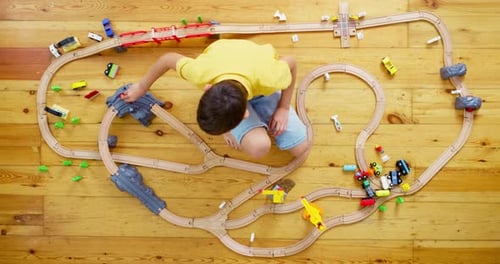Child Playing with Toy Train Set on Floor