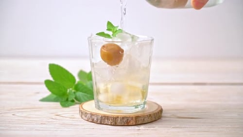 Glass with Ice and Fruit Being Poured