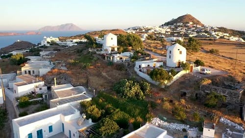 Drone straight fly over traditional windmill style converted homes in the Greek Isles Milos with cat