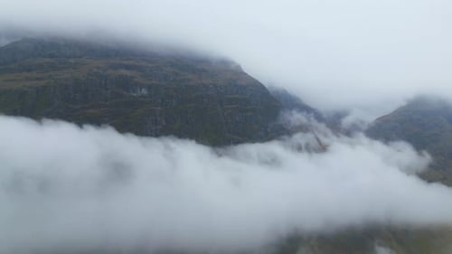 Misty Glencoe mountains shrouded in thick clouds on a foggy day, aerial view