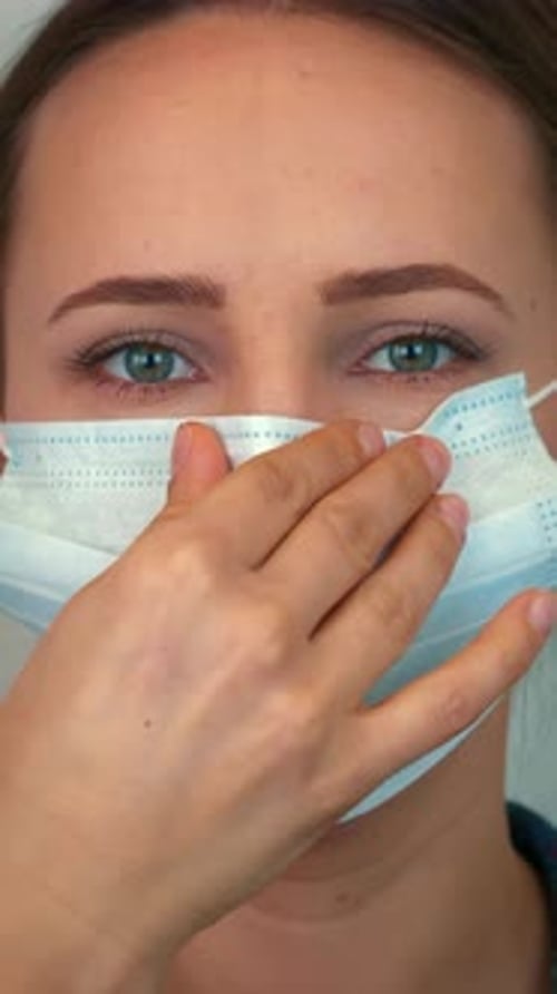 Woman puts on protective medical face mask, close up of face. Vertical video