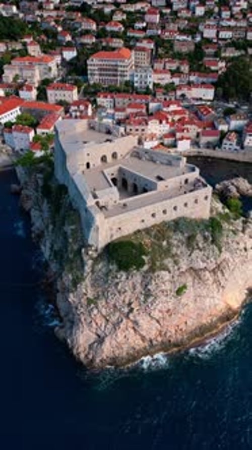 aerial portrait drone shot flying down tracking fort lovrjenac on Adriatic blue sea cliff coast