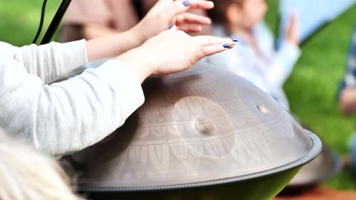 Manos tocando la percusión cuelgan tambores en la naturaleza para meditar y sanar con sonido