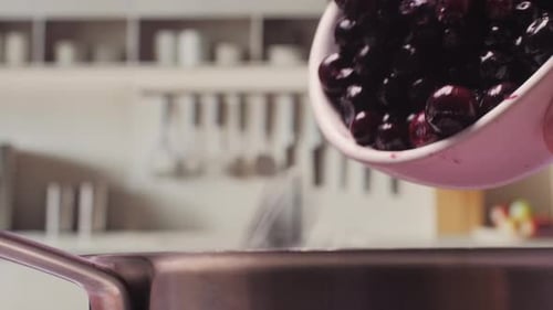 Cherries Falling from Bowl into Pan in Kitchen
