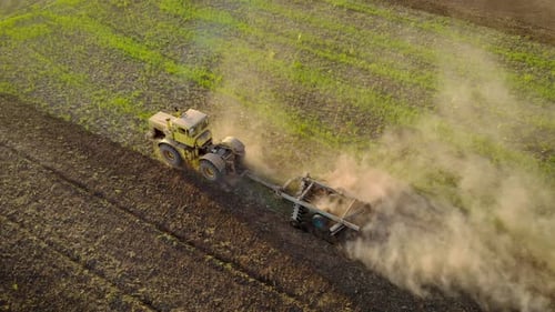 Aerial View of Tractor Pulls Disc Harrow Through Field and Loosens Ground in Preparation for