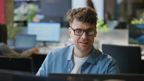 Lächelnder Programmierer arbeitet am Computer am Firmenarbeitsplatz, Nahaufnahme, Mann sucht PC
