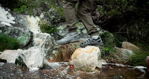 Feet, person and rocks for hiking outdoor with water path, travel journey