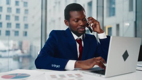 Multitasking Businessman in Office Black Man Talking By Phone Typing on Laptop Professional of