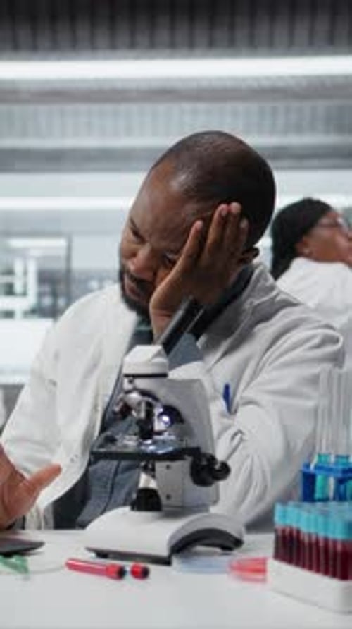 Scientist sits at lab bench with microscope