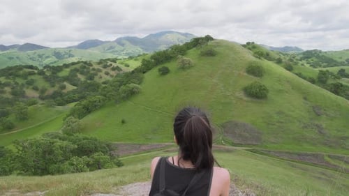 Young Female Hiker Taking a Break From the Hiking Trail In the Green Hills of California
