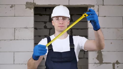 Portrait of a Male Construction Worker in a Helmet Holding Ing a Roulette Wheel