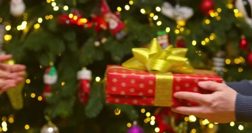 Male Hands Giving Present Gift in Christmas Wrapping Paper to Female Hands