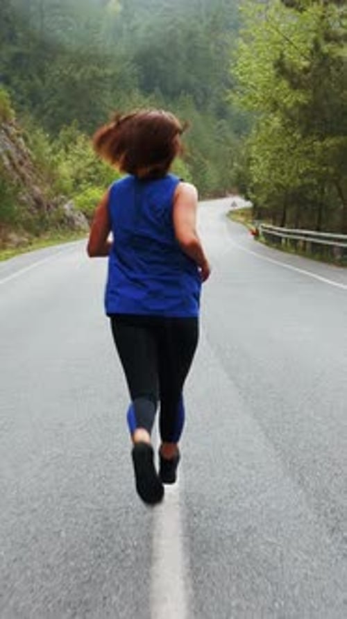 Woman Runs Along Road in Forest