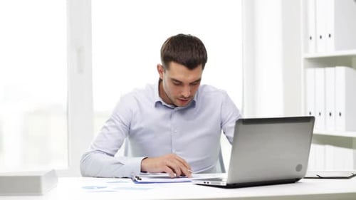 Man Reviews Charts at Desk in Bright Office