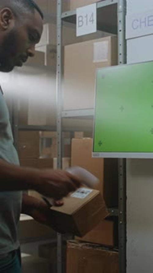 African American Warehouse Associate Checks Parcel Information at Terminal
