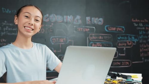 Süßes asiatisches Mädchen-Programmiersystem mit Laptop an der Tafel. Erbauung