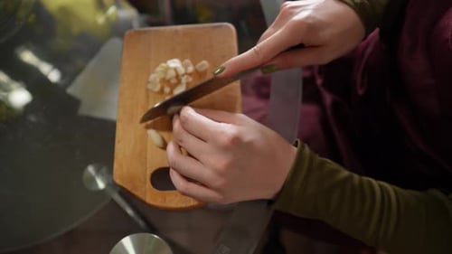 Woman Slicing Fresh Garlic on Cutting Board