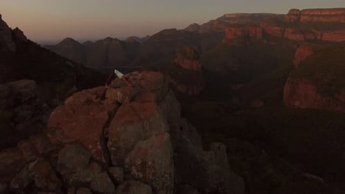 Serene yoga girl meditating at cliff edge on mountain top for wellness in nature