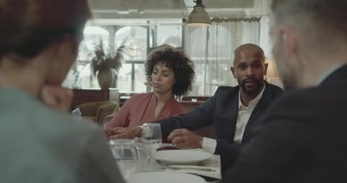 Group of Businesspeople having a Meeting in a Restaurant, using Laptop