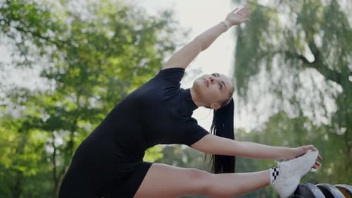 Young Woman Practicing Stretching Exercises in a Park