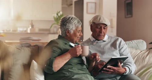 Senior Couple Using Tablet on Couch at Home
