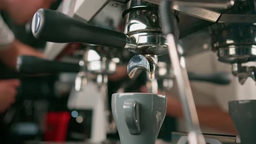 Pouring coffee flows from the machine into the cup making hot drink using the filter holder freshly