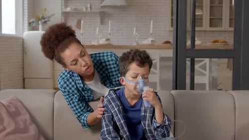 Caring Black Mother Supporting Unwell School Age Son In Nebulizer Mask