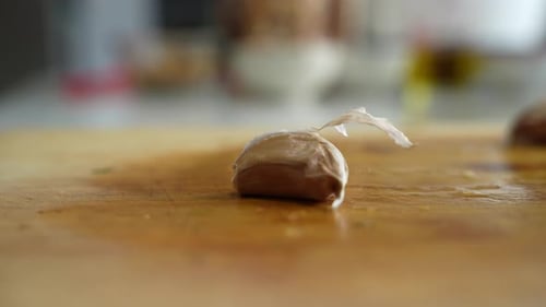 Crushing of garlic cloves using palm of chef in kitchen.