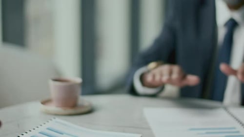 Close-Up of Businessman Showing Thumbs Up and Giving Handshake to Colleague