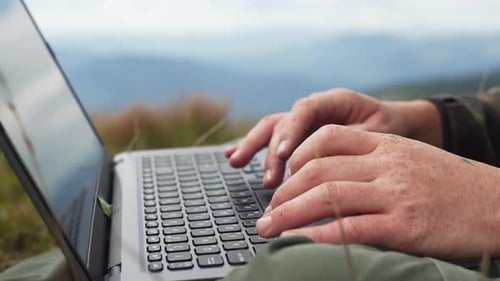 Working on a Laptop in the Mountains Closeup of Male Hands on the Keyboard