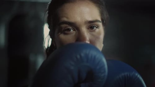 Focused woman boxer with blue boxing gloves