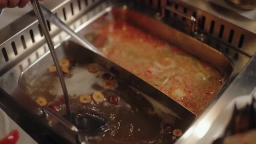 Person Stirring Divided Hot Pot Broth