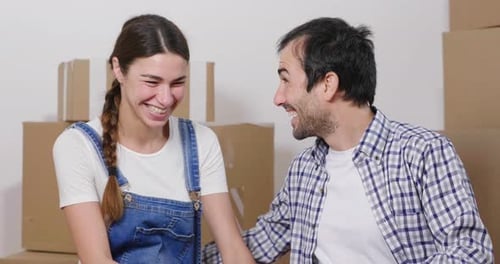 Portrait of a couple in love seated on the floor and they just bought a house and are moving. The