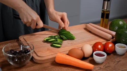 Woman Slices Cucumber and Tomato on Wooden Board