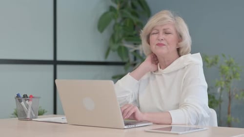 Woman Massaging Neck While Typing at Computer