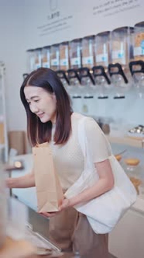 Asian woman shopping with paper bag in a sustainable zero waste refill store
