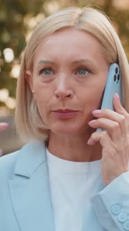 Angry Mature Caucasian Businesswoman Arguing While Talking on Smartphone Standing on City Street