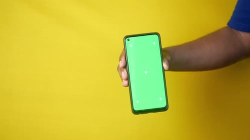 Holding a Smartphone with a Green Screen Against a Bright Background