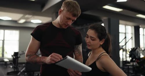 Trainer and Client Discuss Fitness Plan at Gym