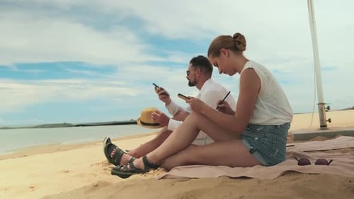 Adults Using Cell Phones at Beach Resort