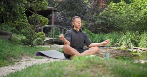 Young African American Spirituality Man Meditating Yoga Asana Sitting in a Park Outdoor