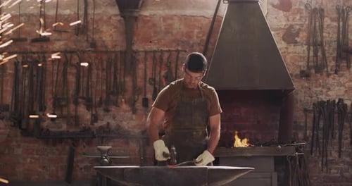 Blacksmith, fire and man with hammer on anvil in workshop for forging iron, steel or metal
