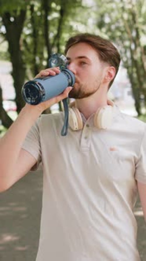 Sporty Athletic Thirsty Man Runner Jogger Drinking Water After Sport Workout in Park Outdoors