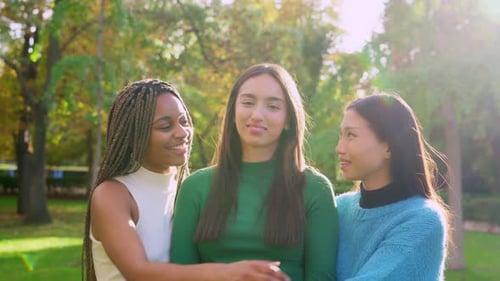 Amigos multiétnicos felizes abraçando e sorrindo no parque